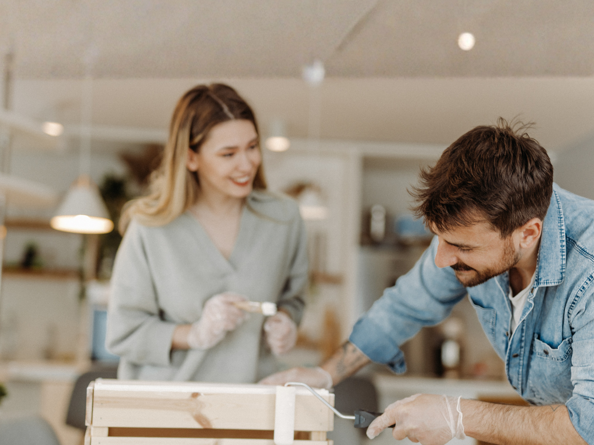 Persona dipinge una cassetta di legno durante un laboratorio di bricolage creativo nell'Officina del Fai da Te di Abilmente.