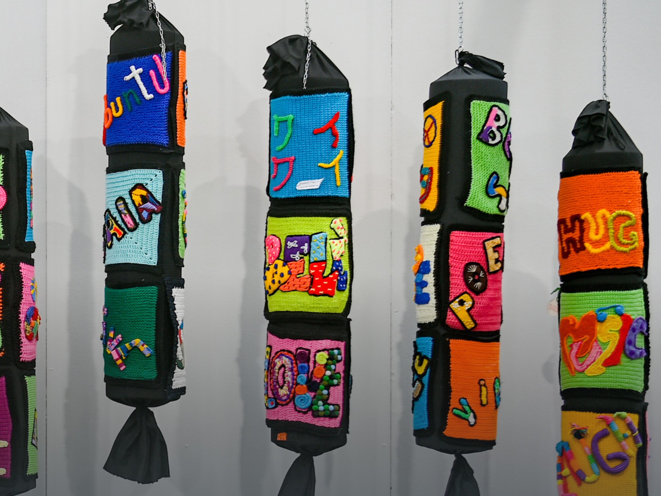 Installazione artistica tessile con opere colorate realizzate a maglia e uncinetto esposte alla mostra di Abilmente
