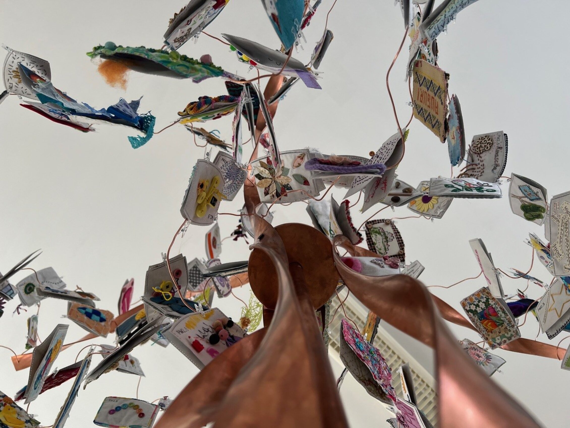 Dettaglio dell'installazione artistica tessile Vita Viva con opere ricamate sospese e struttura ad albero in mostra ad Abilmente