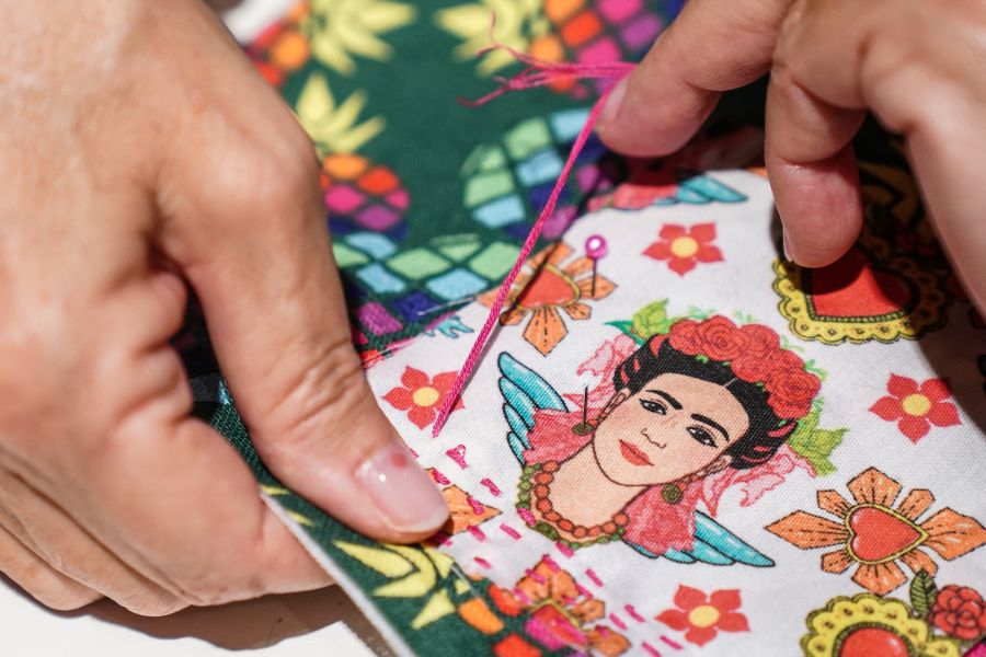 Mani che cuciscono una toppa con frida kahlo